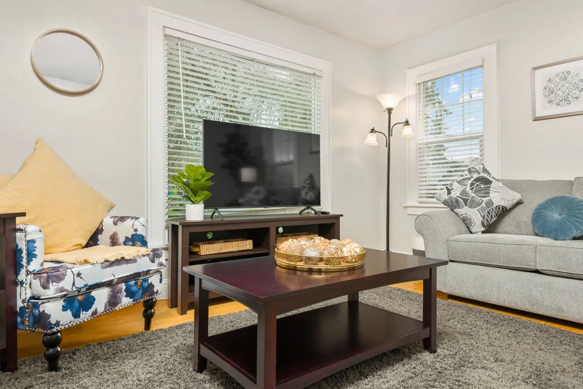 A cozy living area highlighting a soft sofa, coffee table, television, and a comfortable armchair. The arrangement encourages both intimate conversations and group gatherings, supporting a range of activities from watching TV to relaxing with friends.