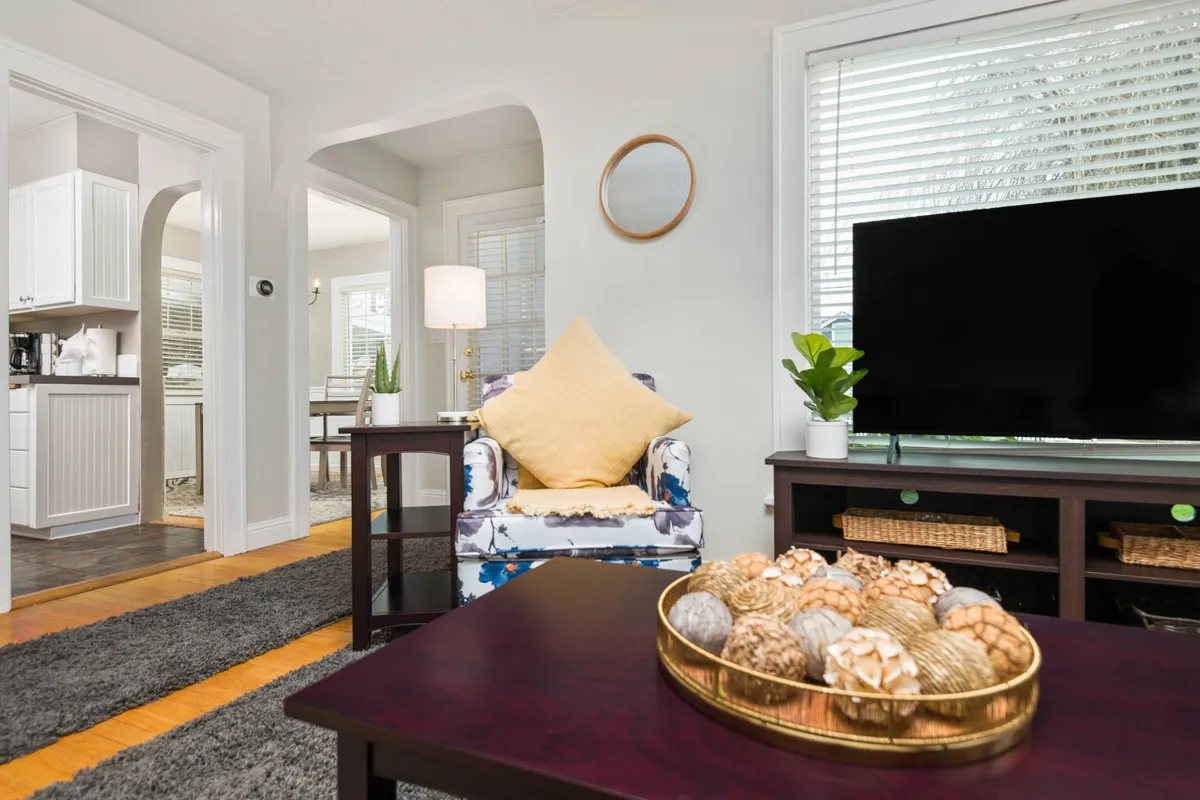 A cozy and inviting living space with a colorful armchair, decorative bowl on the table, and a TV. The arrangement encourages relaxation and casual gatherings, hinting at moments of planning or reminiscing about local travel adventures.